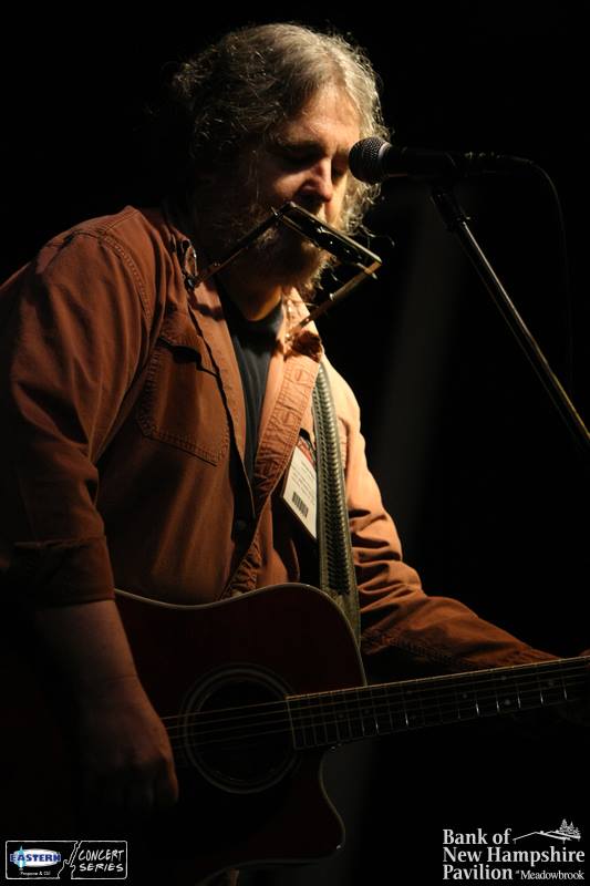 Promotional photo of Justin Jaymes performing at a show with dark lighting.